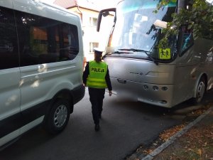 Policjantka idąca pomiędzy autobusami