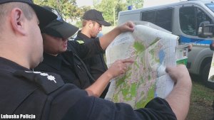 Kilku policjantów zapoznaje się z mapą terenu, na którym mógł zaginąć mężczyzna.