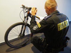 Na zdjęciu widzimy policjanta zabezpieczającego skradziony rower.