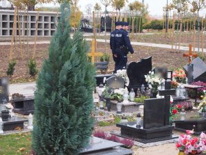 Na zdjęciu widzimy dwóch policjantów patrolujących cmentarz.