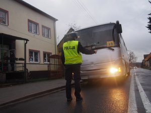 policjantka sprawdzająca przednie oświetlenie autobusu