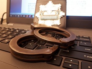 odznaka policyjna i kajdanki na klawiaturze od laptopa