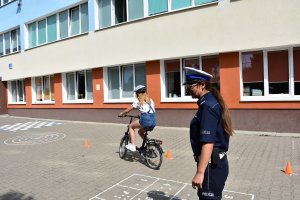 policjantka i dziewczynka na rowerze przed szkołą