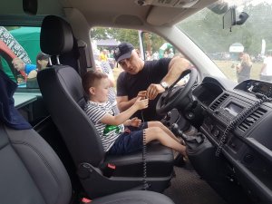 Dziecko z policjantem zwiedzające wnętrze radiowozu na festynie