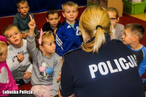umundurowana policjantka, przed nią siedzą dzieci