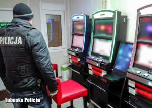 policjant stojący przy trzech automatach do gier