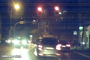 pojazdy na drodze, zapalone czerwone sygnalizatory, taksówka wjeżdżająca na lewy pas