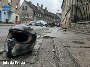 motocyklowy kask leżący na ulicy przy krawężniku, w tle radiowóz