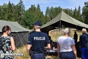 Policjant i Sanepid na kontroli obozów, w tle namioty