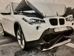 Białe BMW Suv z rozbitym przodem na drodze