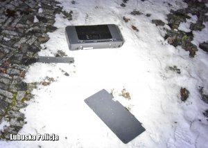 Urządzenie rozpołowione leżące na śniegu na kamienistej drodze