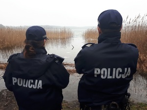 Dwoje policjantów stojących nad brzegiem jeziora.