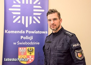 Policjant w mundurze na tle baneru Policja Świebodzin