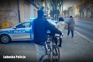 Radiowóz, rowerzysta i policjantka na chodniku