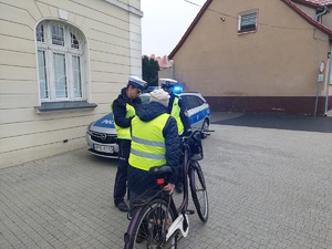 Radiowóz a przed nim policjantka rozmawia z rowerzystką.