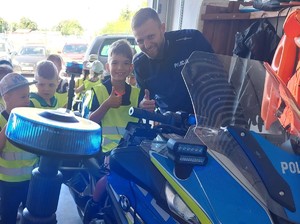 Policjant z dziećmi przy motocyklu.
