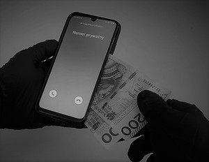 Telefon w ręku z którego wyciągane są dwa banknoty, na wyświetlaczu napisane numer prywatny.