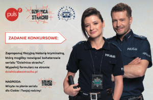 Dwójka aktorów przebranych za policjantów na tle plakatu informującego o konkursie.