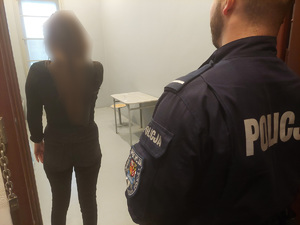 Kobieta w celi, na pierwszym planie policjant.
