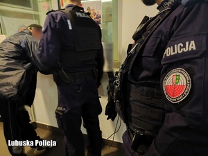 Policjanci z oddziałów stoją przy mężczyźnie przy okienku na komendzie.