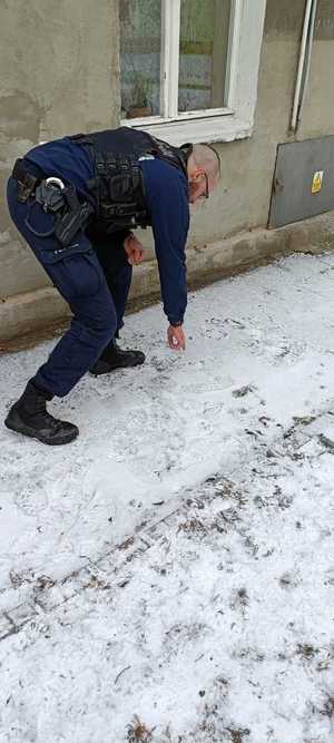 Policjant wskazujący ślady na śniegu
