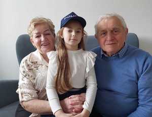 Babcia i dziadek z wnuczka w czapce policjanta.